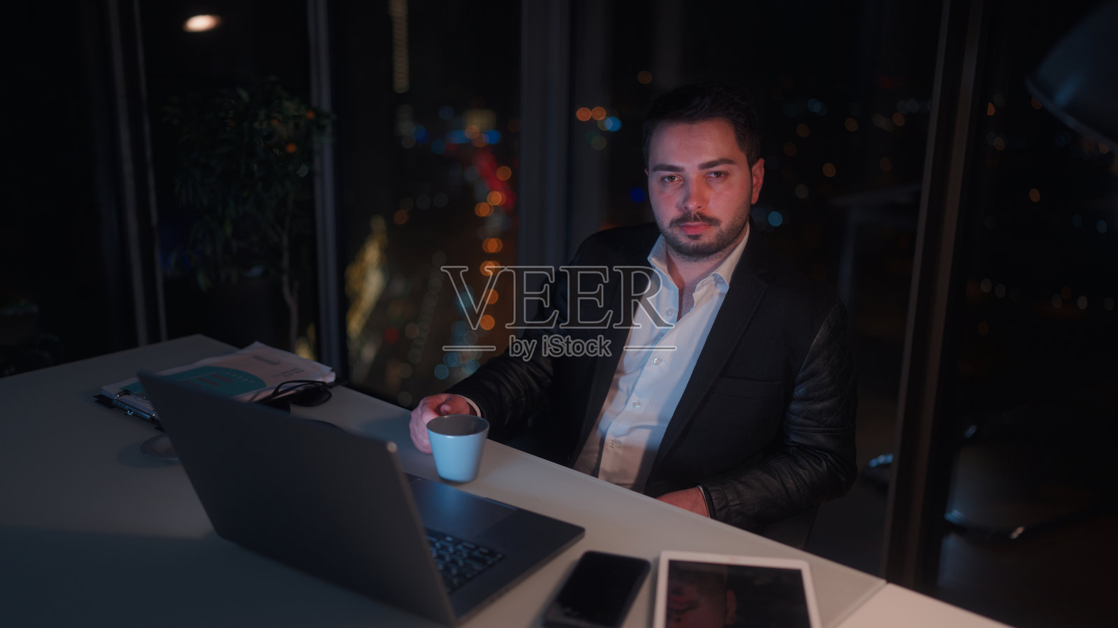 年轻的商人在办公室工作到深夜的肖像照片摄影图片