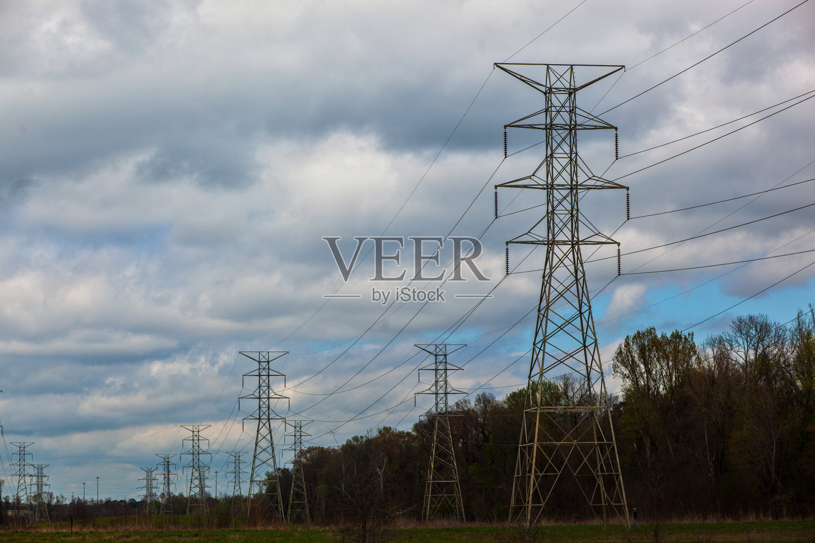 一排输电塔映衬着多云的天空照片摄影图片