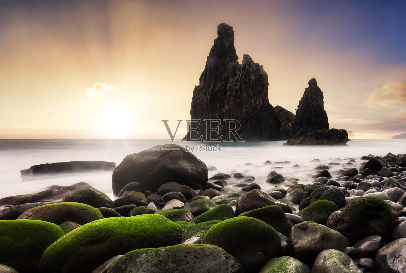 日出在岩石海岸，巨大的岩石悬崖和模糊的海水。葡萄牙马德拉岛照片摄影图片