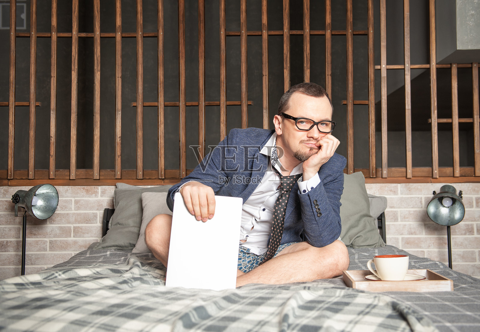 无聊的男人穿着西装和内裤在家上网坐在床上工作照片摄影图片