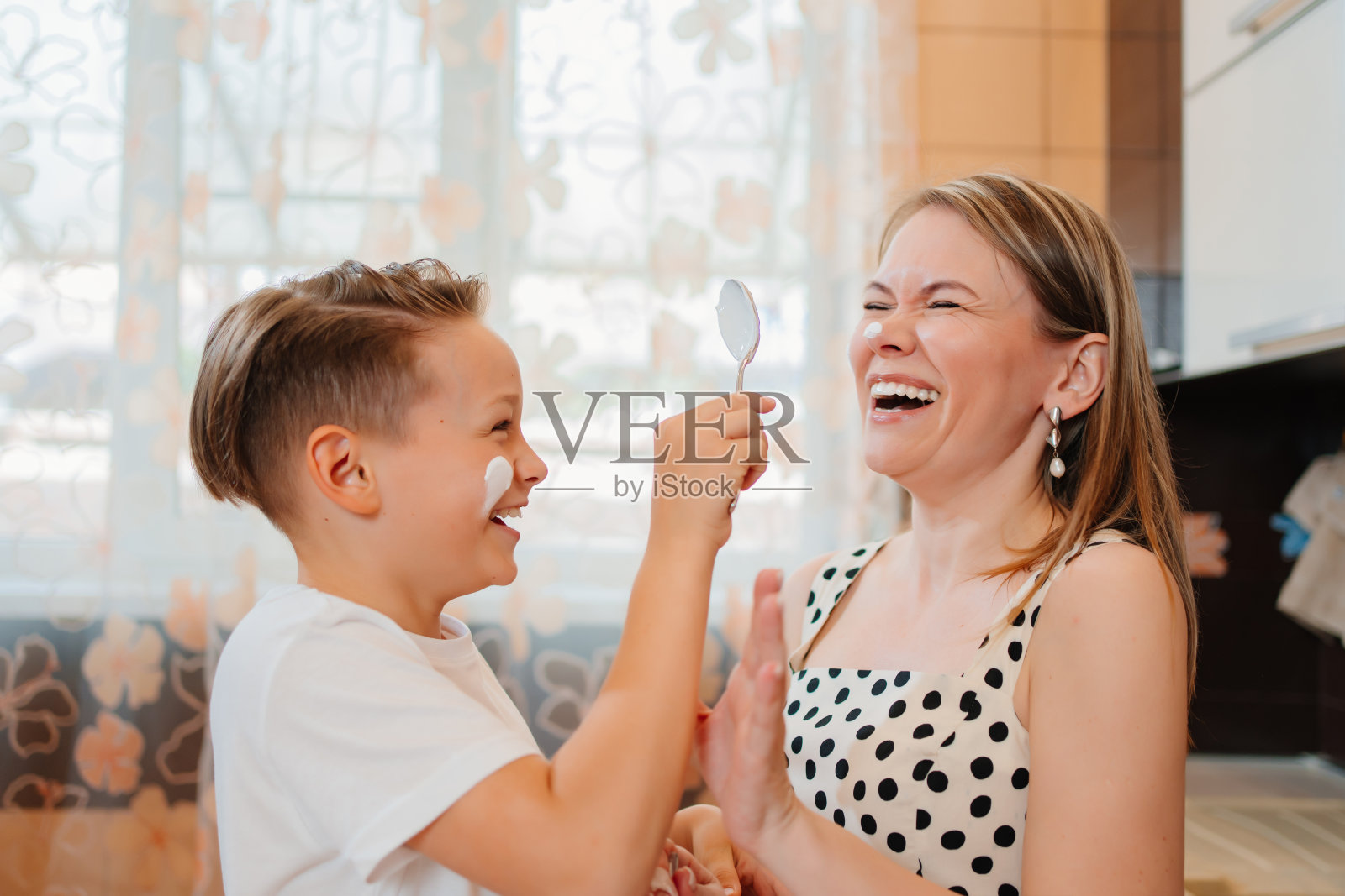 十几岁的母亲和儿子一起做饭，在厨房里玩得很开心。照片摄影图片