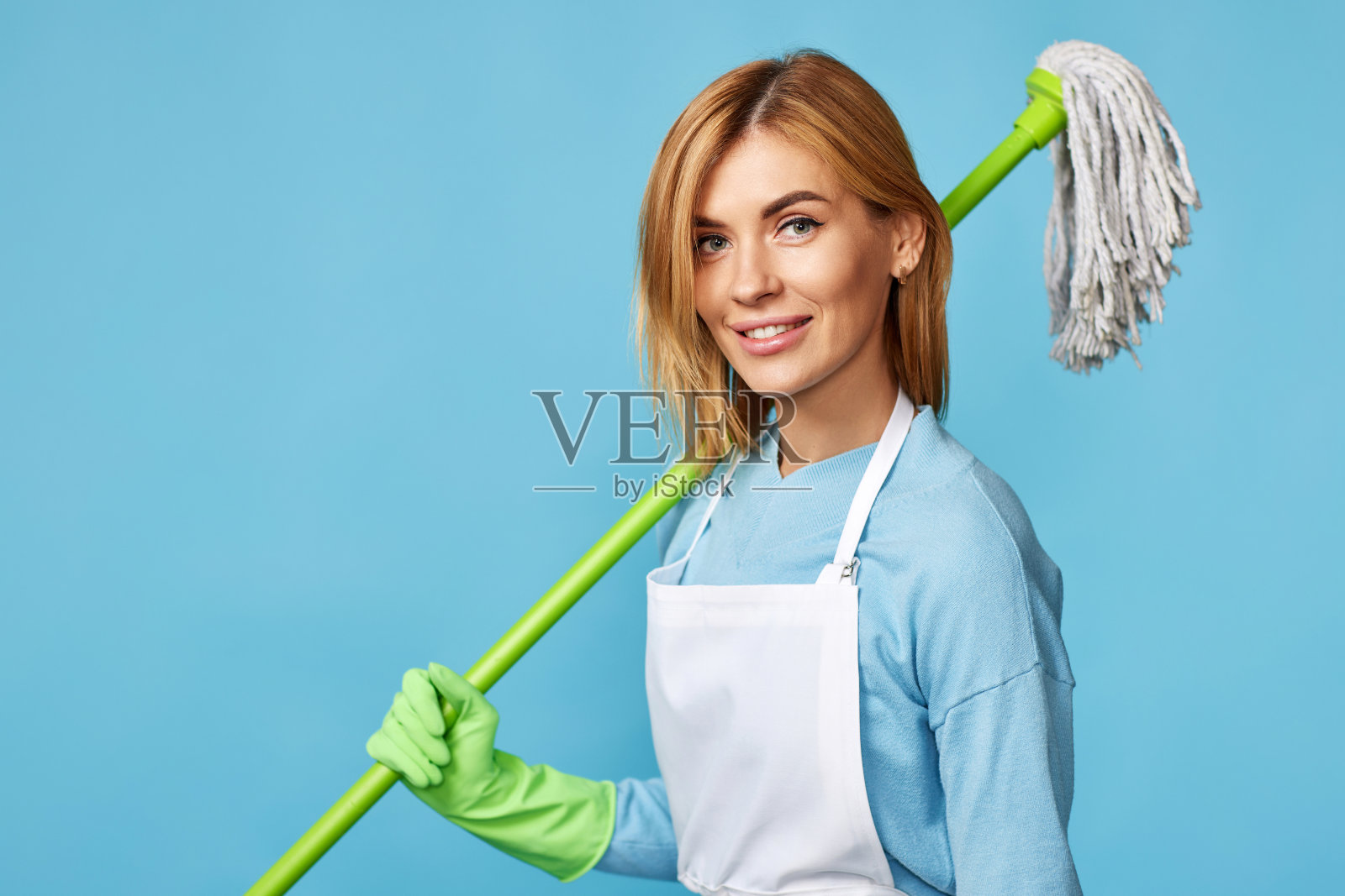 戴着橡胶手套的女人拿着拖把和水桶照片摄影图片