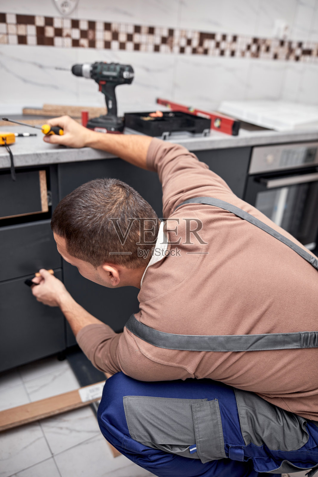 在公寓里做厨房壁柜的杂工。照片摄影图片