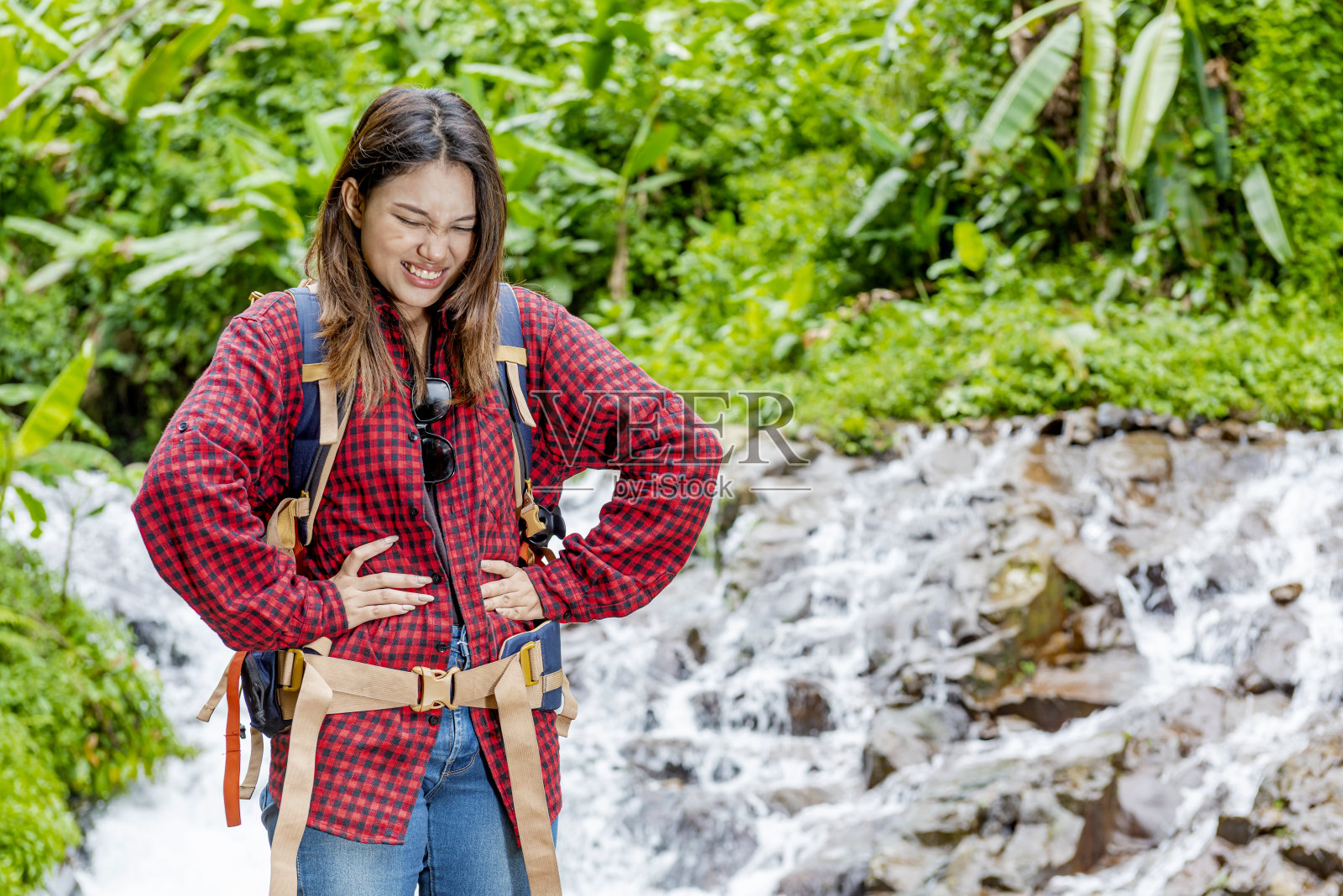 背着双肩包的亚洲女性感觉胃疼照片摄影图片