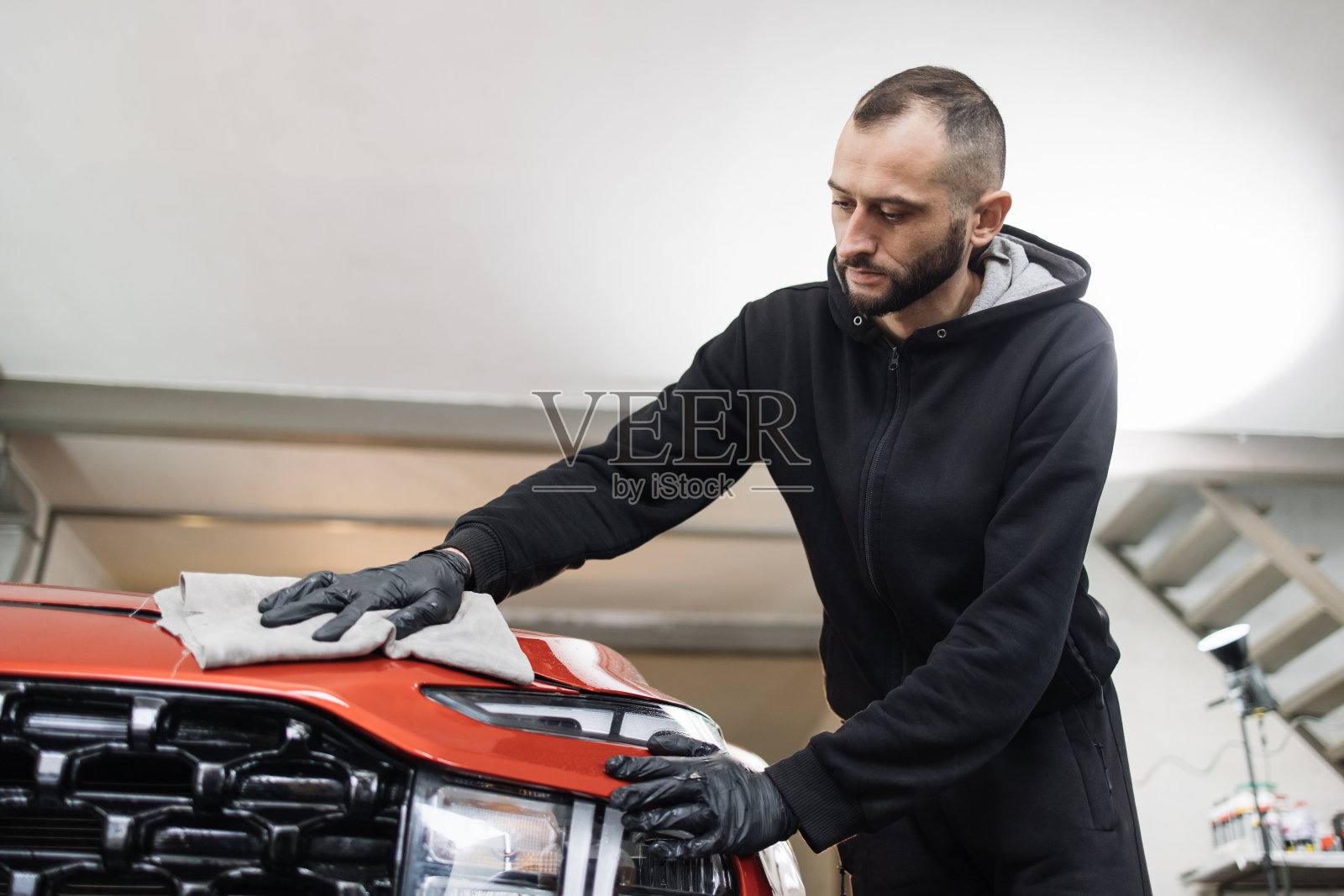 年轻英俊的大胡子洗车工人男子，穿着防护服和手套照片摄影图片