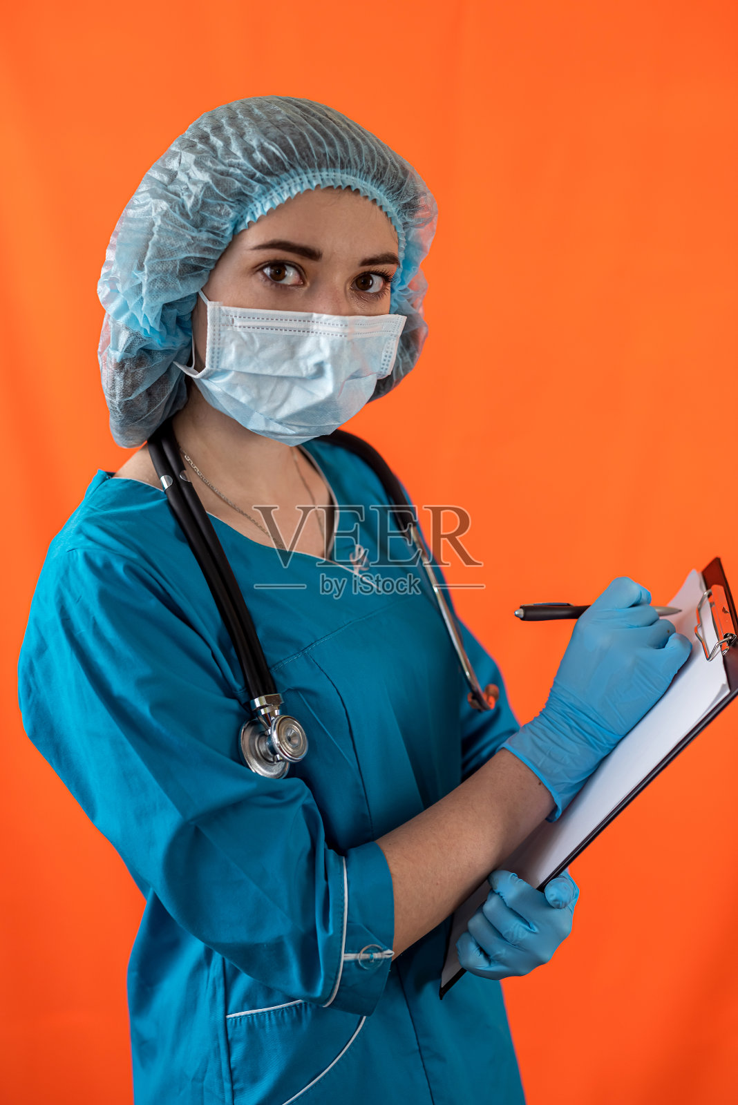 微笑的护士与美丽的微笑拿着一个剪贴板孤立在一个朴素的背景照片摄影图片