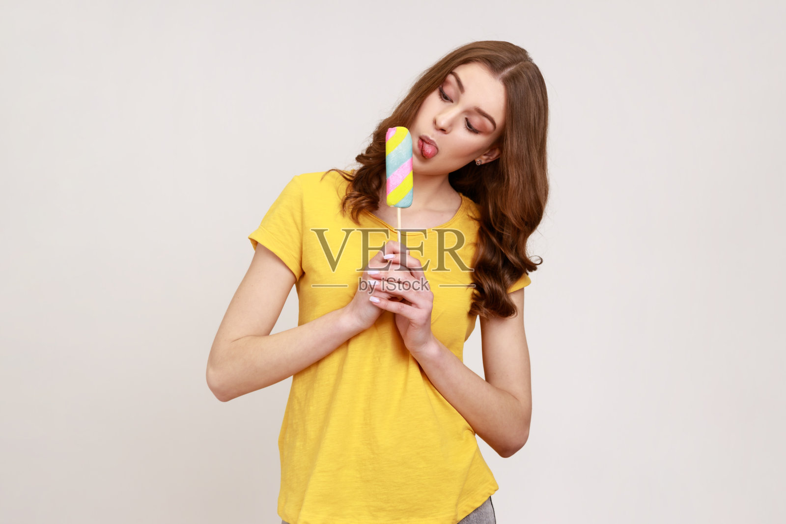 有趣的少女肖像伸出舌头舔冰淇淋，品尝和享受美味的风味甜点，甜甜的糖果。照片摄影图片