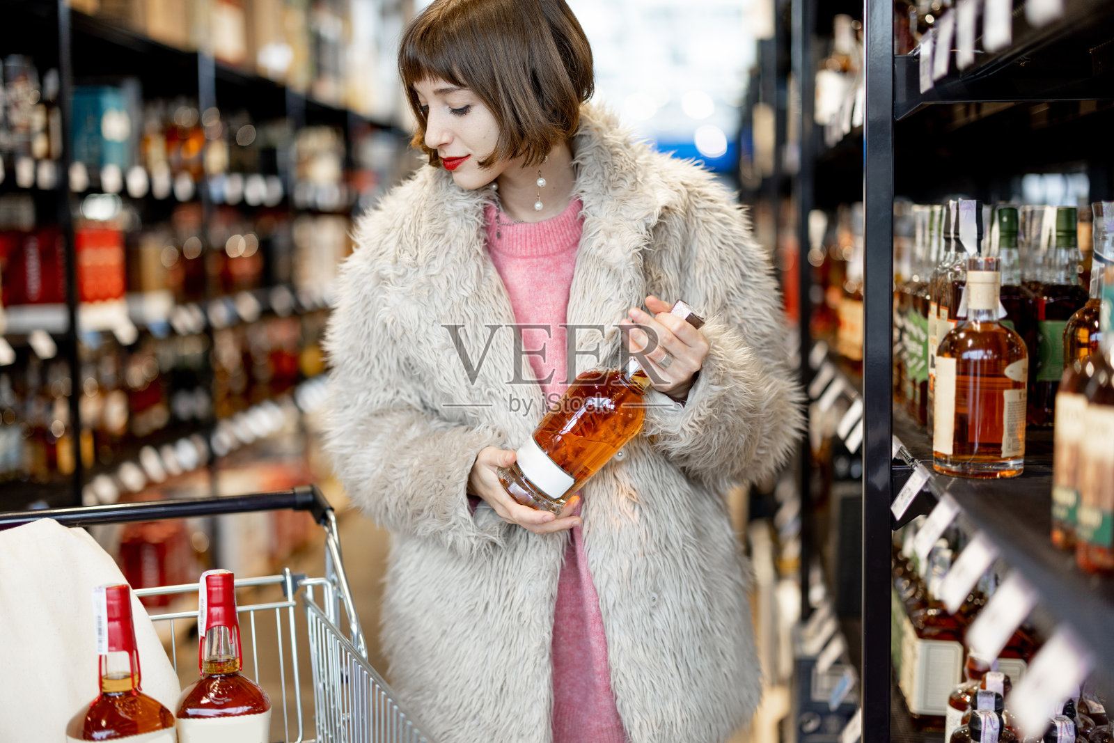 女子在超市挑选烈性酒照片摄影图片