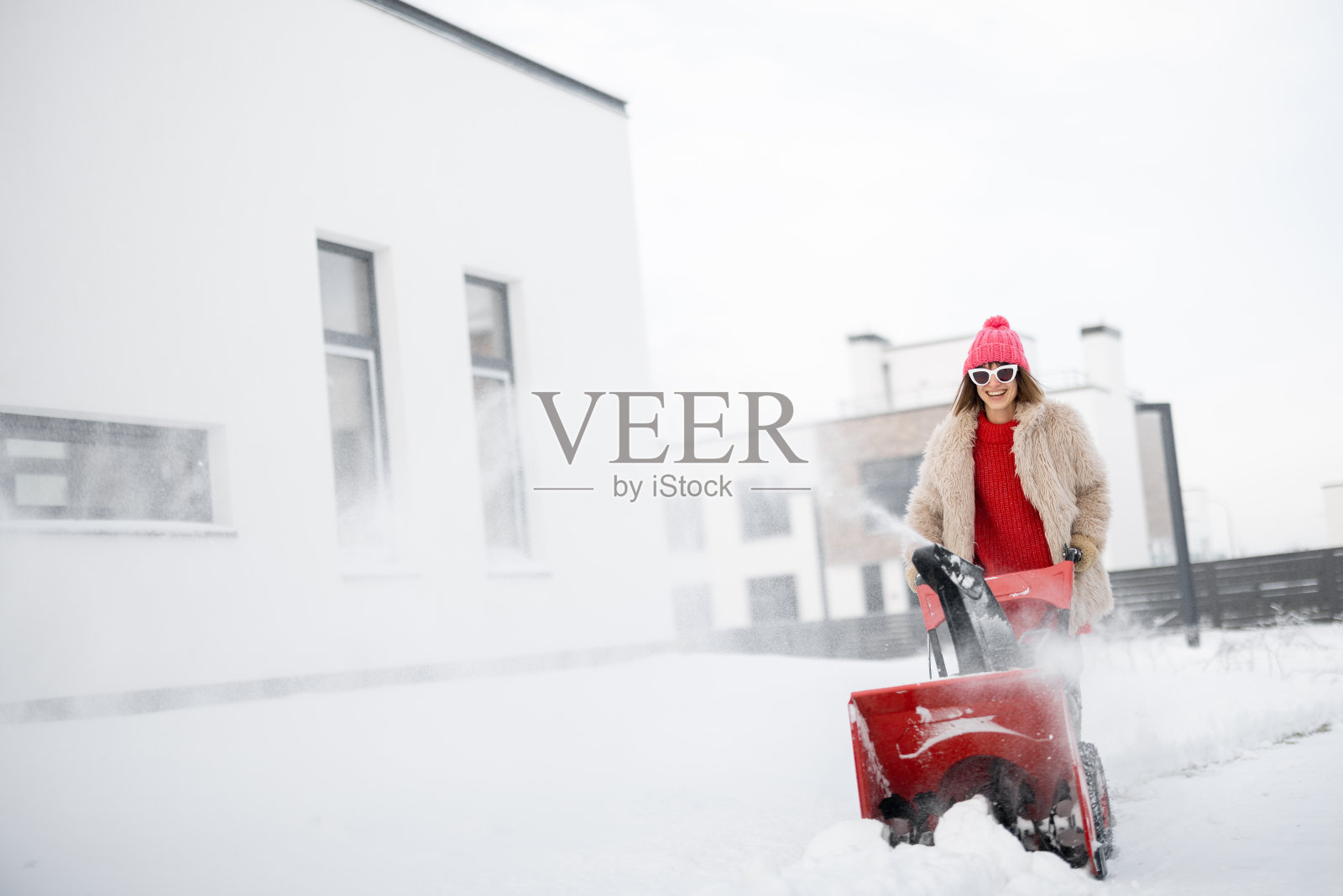 一名妇女在房子附近用除雪机除雪照片摄影图片