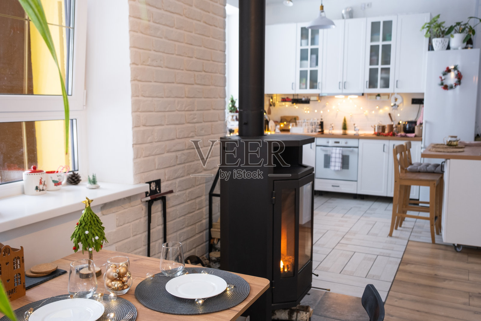 房子的节日内部装饰为圣诞节和新年的阁楼风格，有黑色的火炉，壁炉，圣诞树。温暖的工作室，白色厨房，燃烧的木材，舒适和温暖的家照片摄影图片
