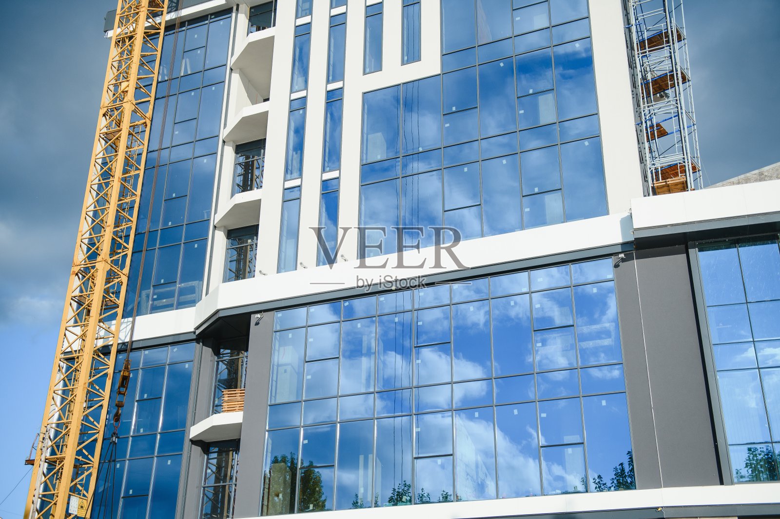 建筑起重机站在建造房屋的附近照片摄影图片