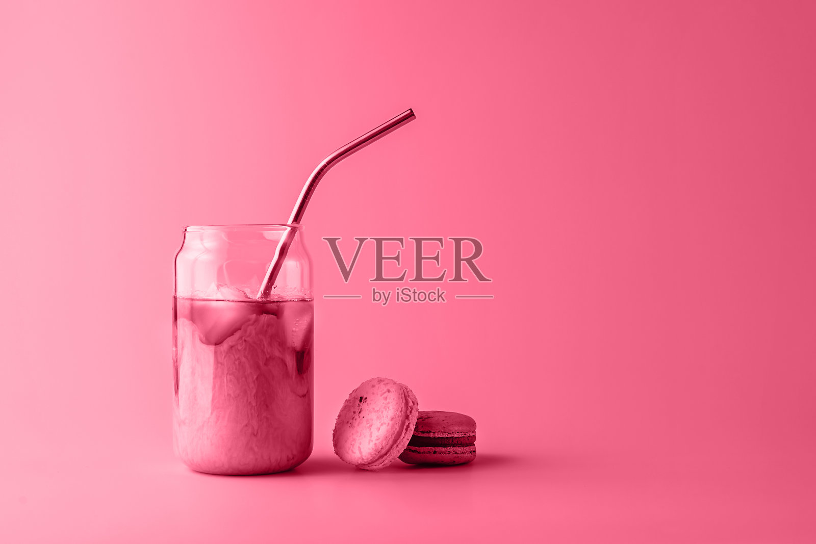 一杯高脚杯冰咖啡，加奶油和蛋白杏仁饼，颜色是2023年流行的洋红色。照片摄影图片