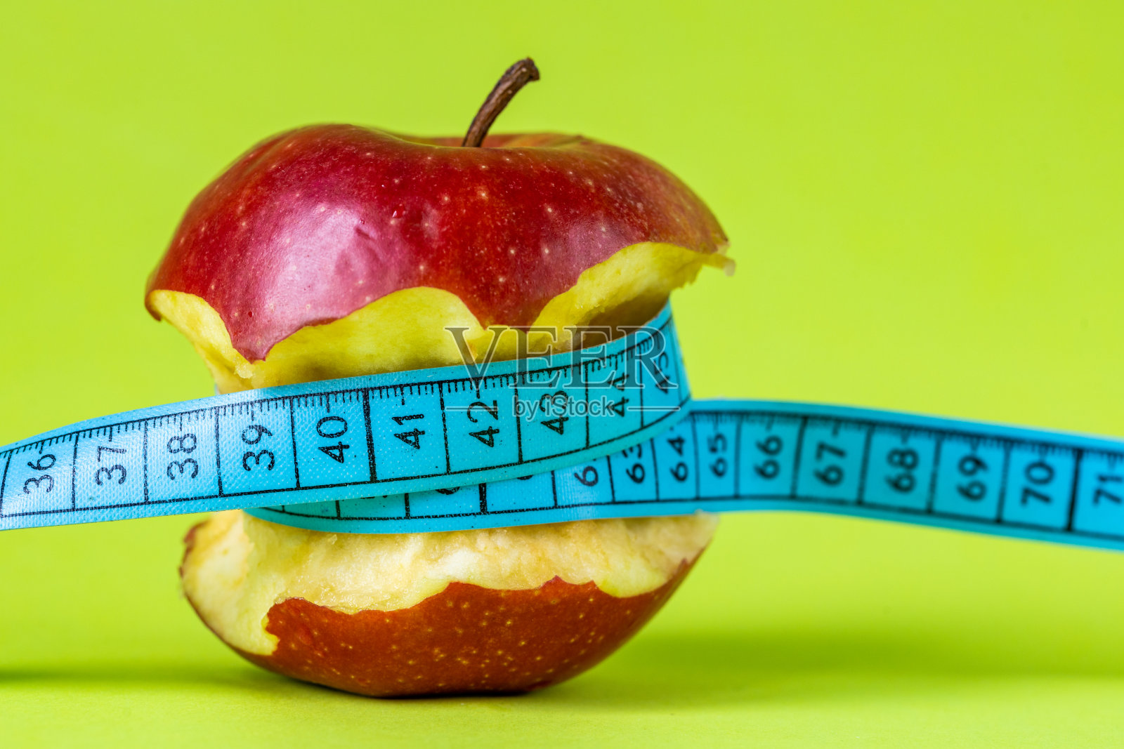 减肥理念，咬苹果相关的裁缝仪表，正面绿色背景，健康美味，积极的饮食方法，特写照片摄影图片