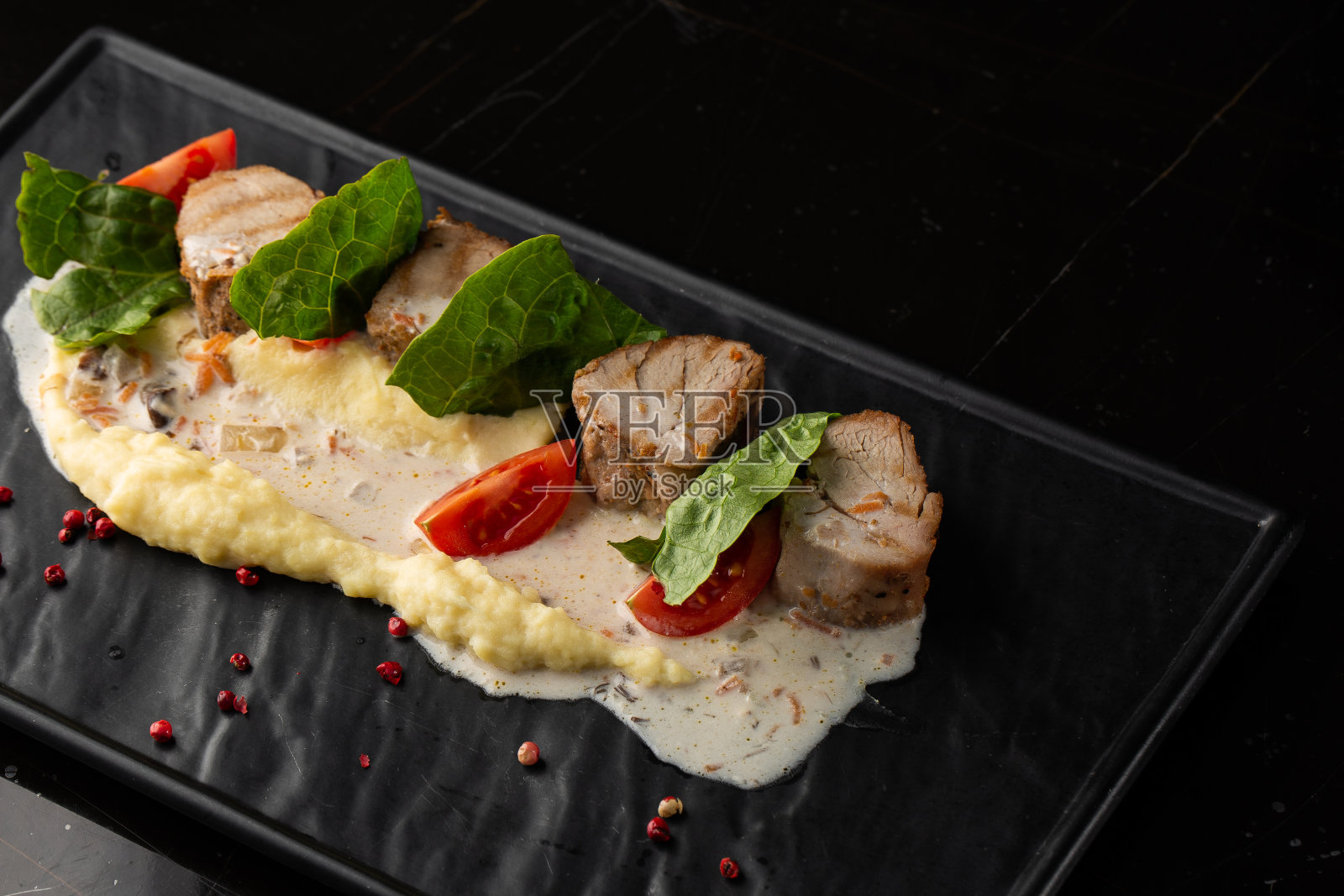 白盘上的烤肉和土豆泥配菜。黑色背景上的微距特写。美味佳肴，餐厅菜单概念照片摄影图片