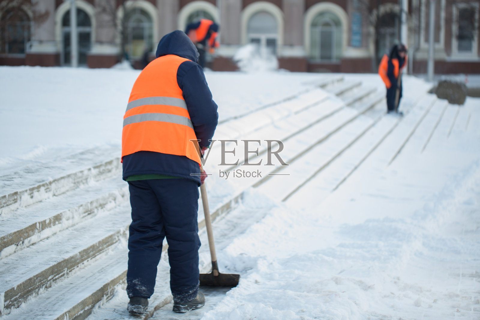 工人们在冬天清扫道路上的积雪，清扫道路上的暴风雪照片摄影图片
