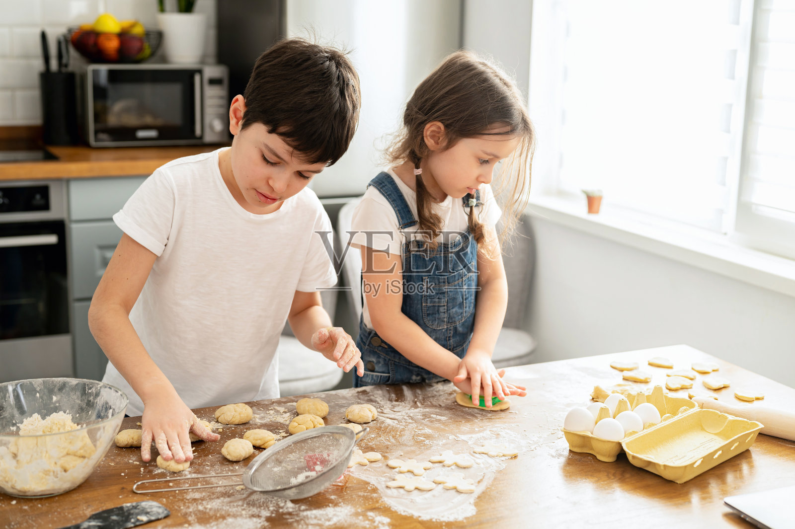可爱的学步男孩和女孩一起做饭，揉面团，用擀面杖，妹妹和弟弟在家打发闲暇，烤饼干照片摄影图片