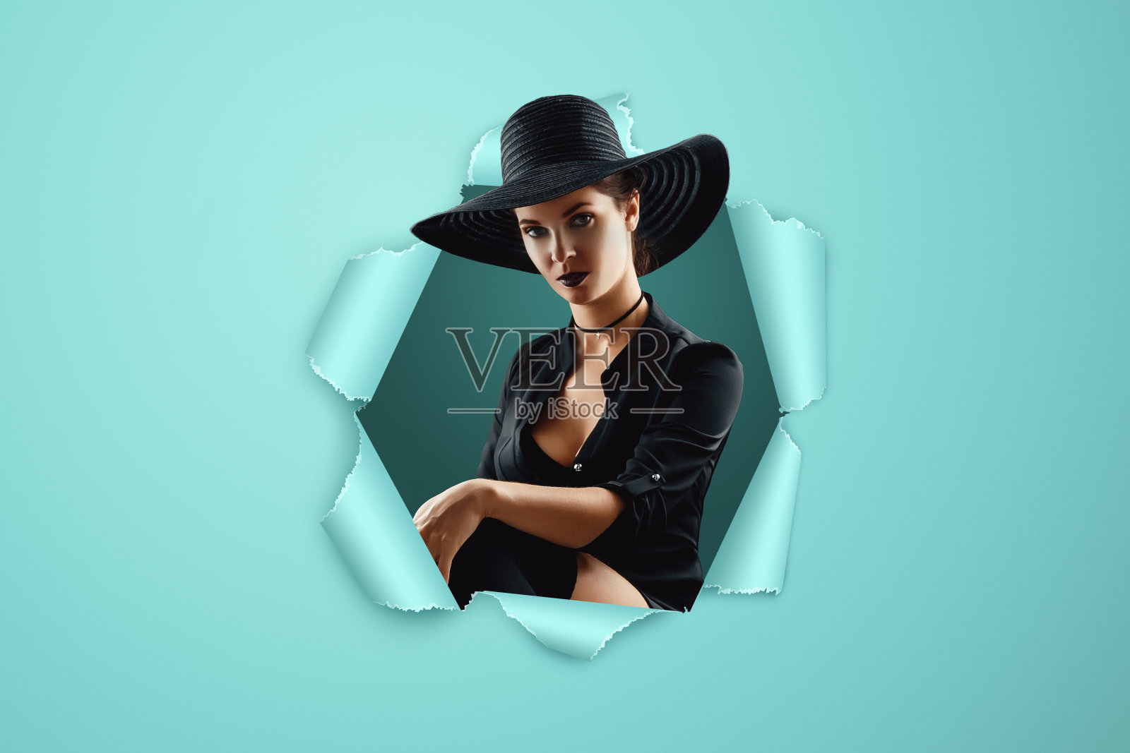 女孩女巫穿着黑色的裙子和帽子，背景是蓝色的打孔纸。照片摄影图片