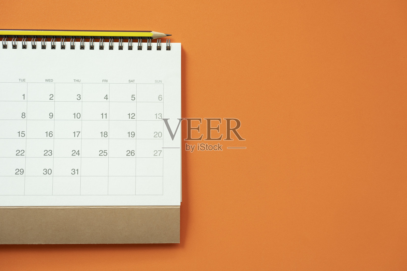 橙色桌子背景上的日历和铅笔特写，用于商务会议或旅行计划的概念照片摄影图片