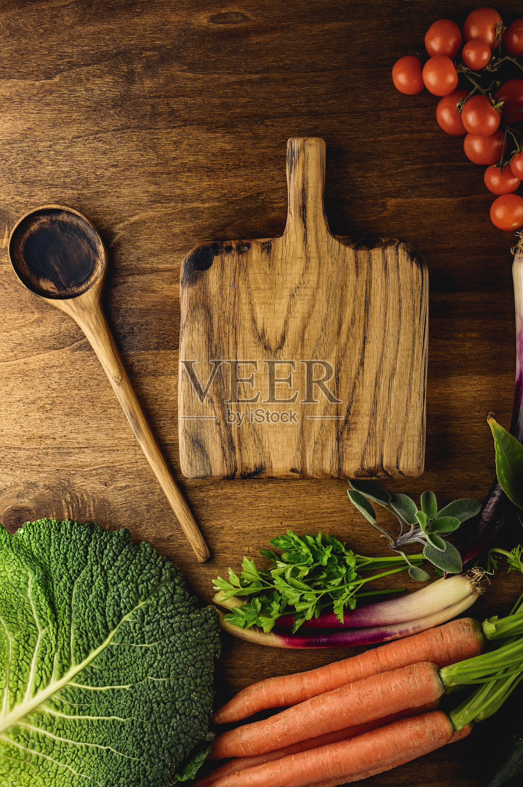 木制的砧板和勺子放在木桌上，周围放着蔬菜照片摄影图片