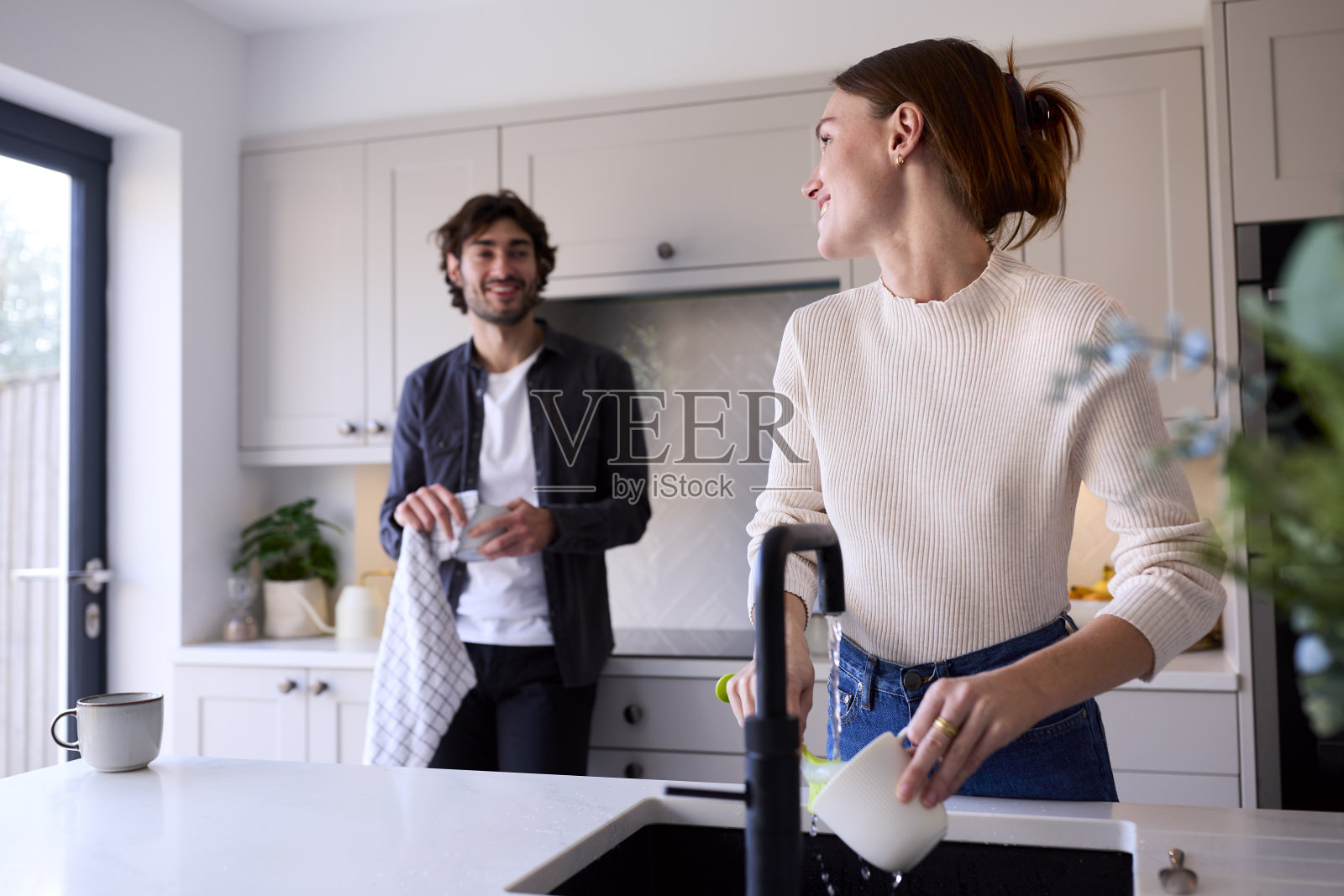 情侣在厨房的家中，女人在洗碗照片摄影图片