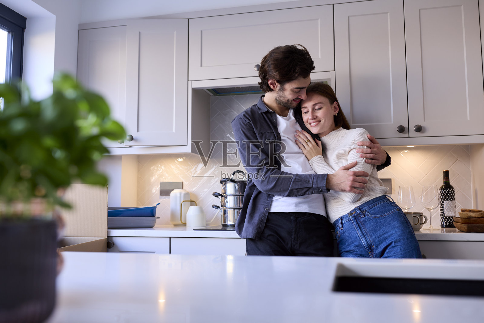 搬进新家在厨房一起打开箱子拥抱的年轻情侣照片摄影图片