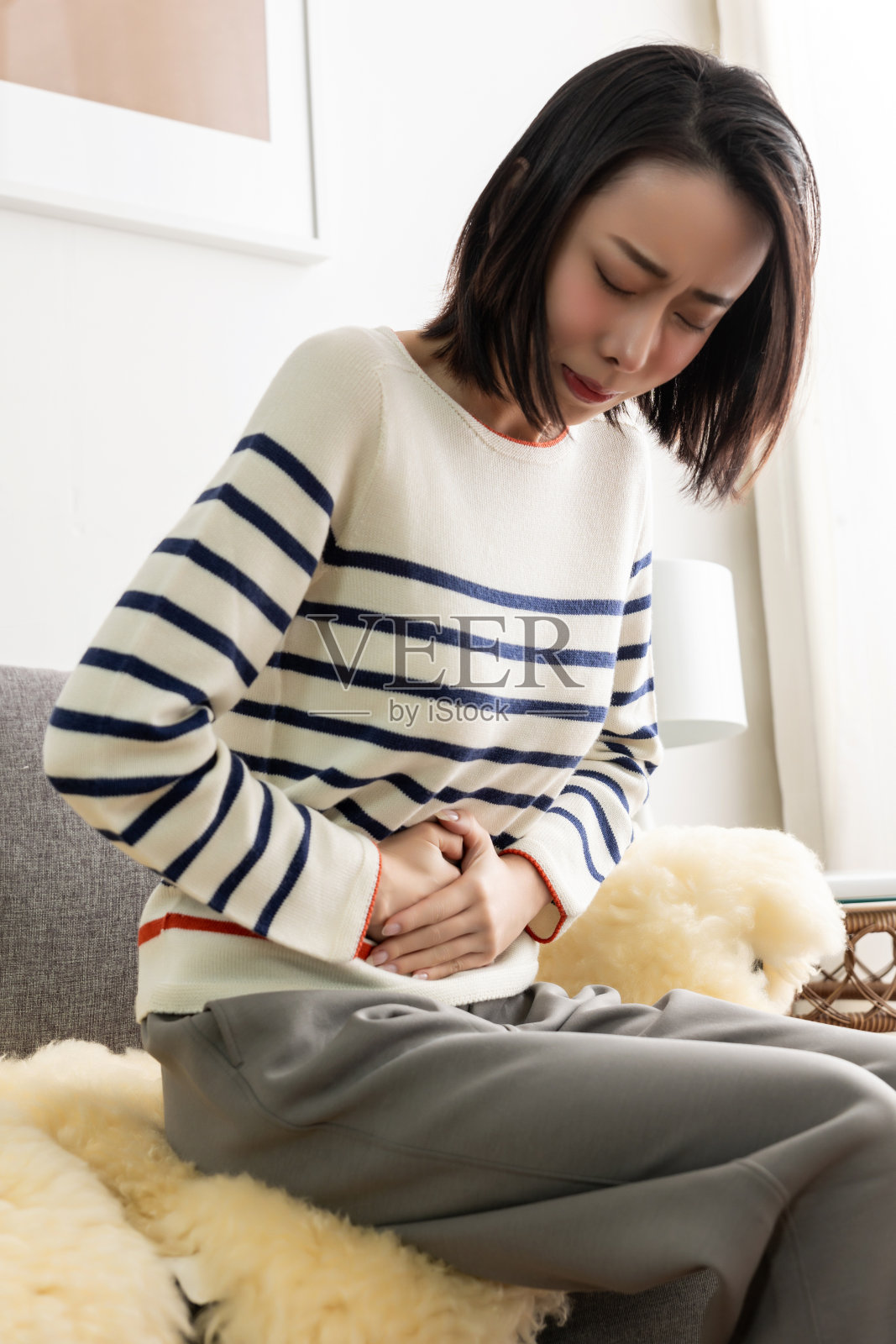 年轻漂亮的亚洲女人躺在客厅舒适的沙发上休息。照片摄影图片