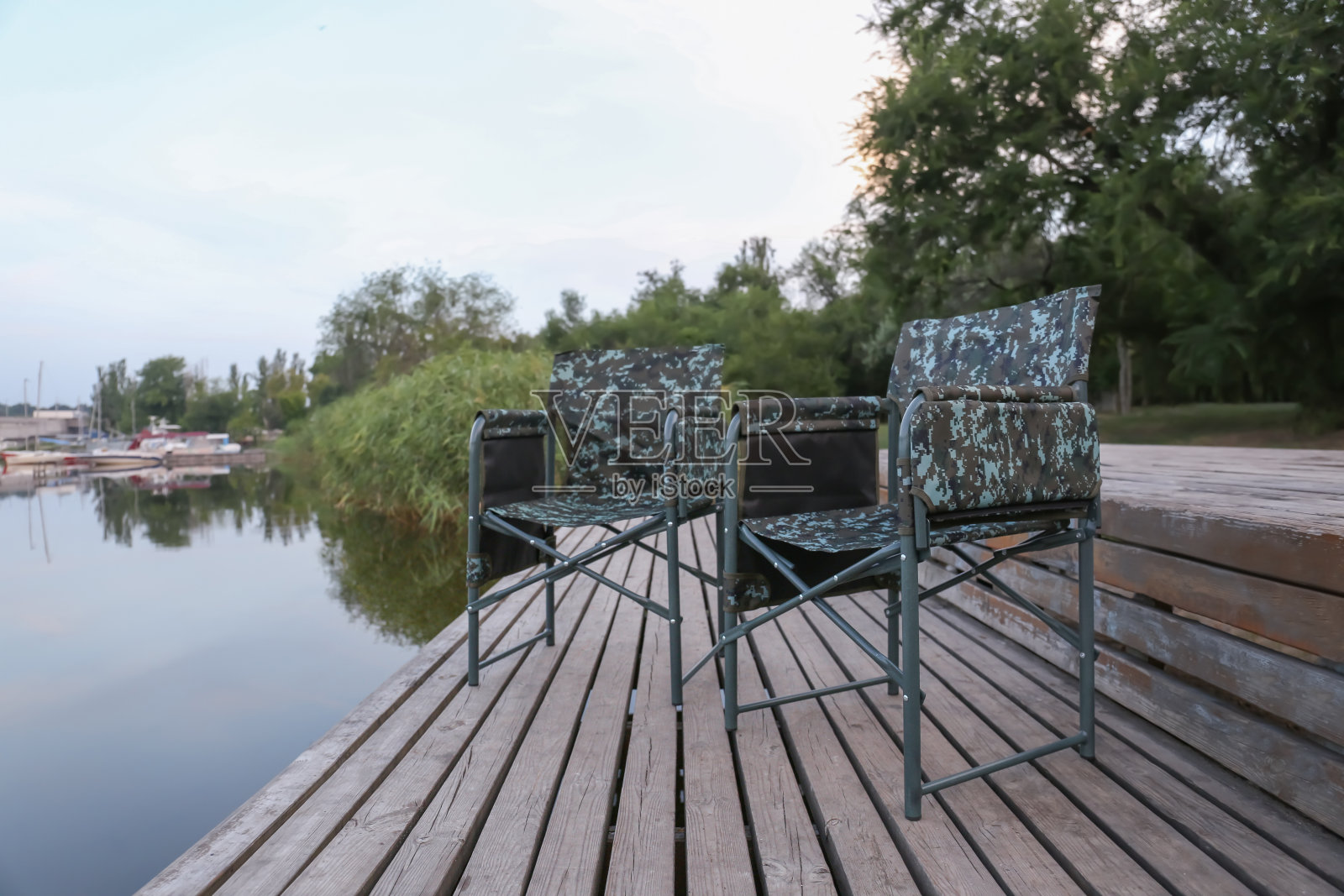 河边木墩上的迷彩钓鱼椅照片摄影图片