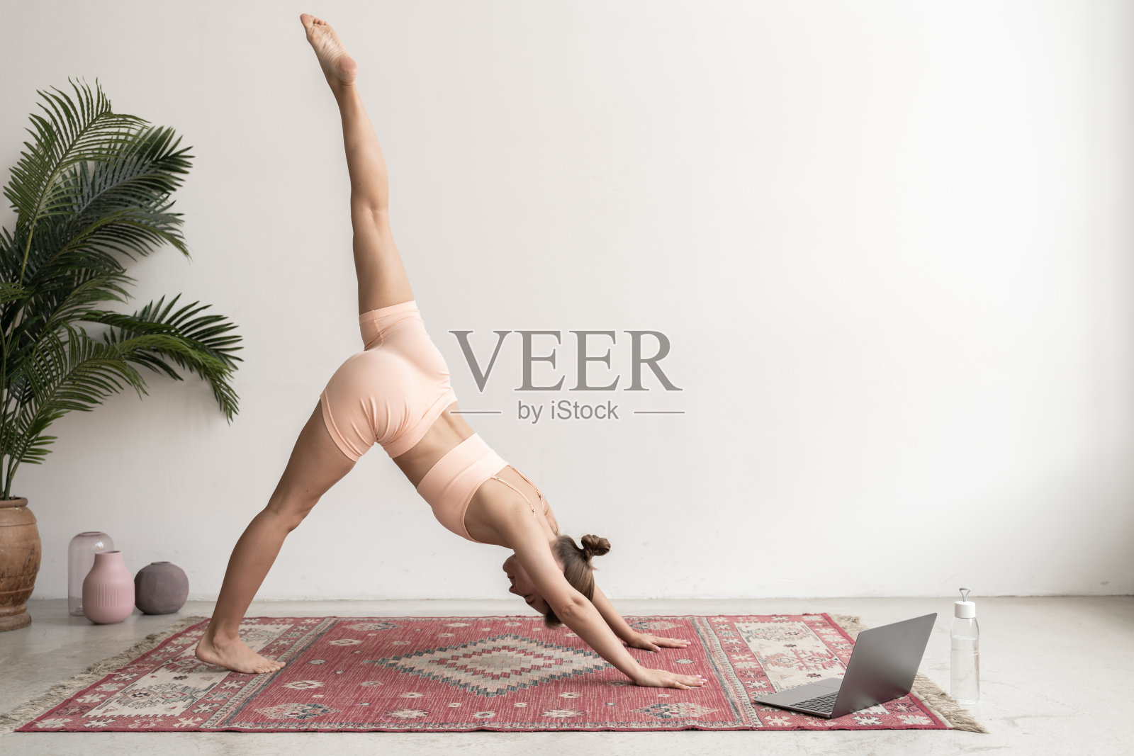 年轻女子练习瑜伽下犬式，adho mukha svanasanaa在家照片摄影图片