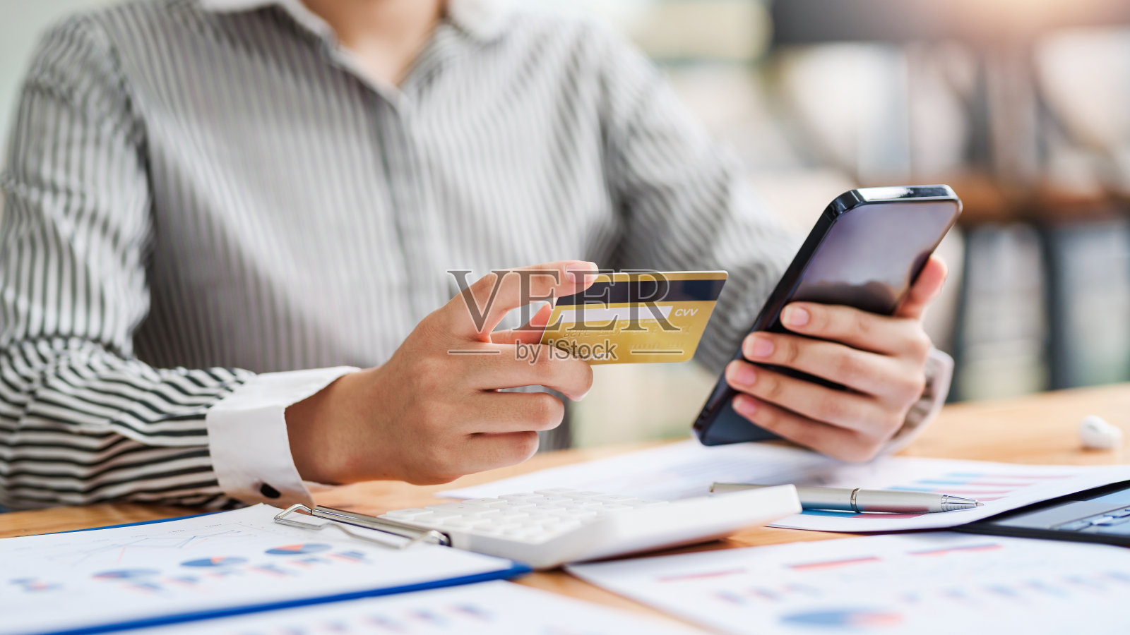 关闭了。手持智能手机使用信用卡网购的女子。照片摄影图片