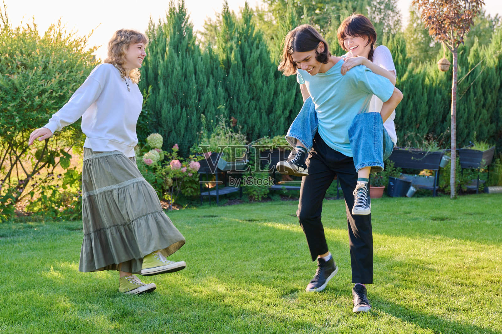 三个十几岁的朋友在阳光明媚的夏日，在户外的草坪上玩耍照片摄影图片