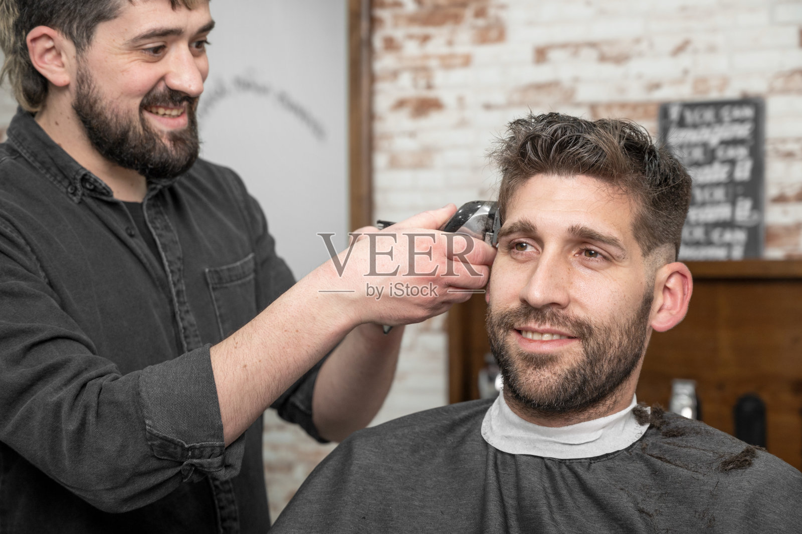 男理发师在理发店用剪子给男顾客理发。弄头发的过程。高质量的摄影照片摄影图片