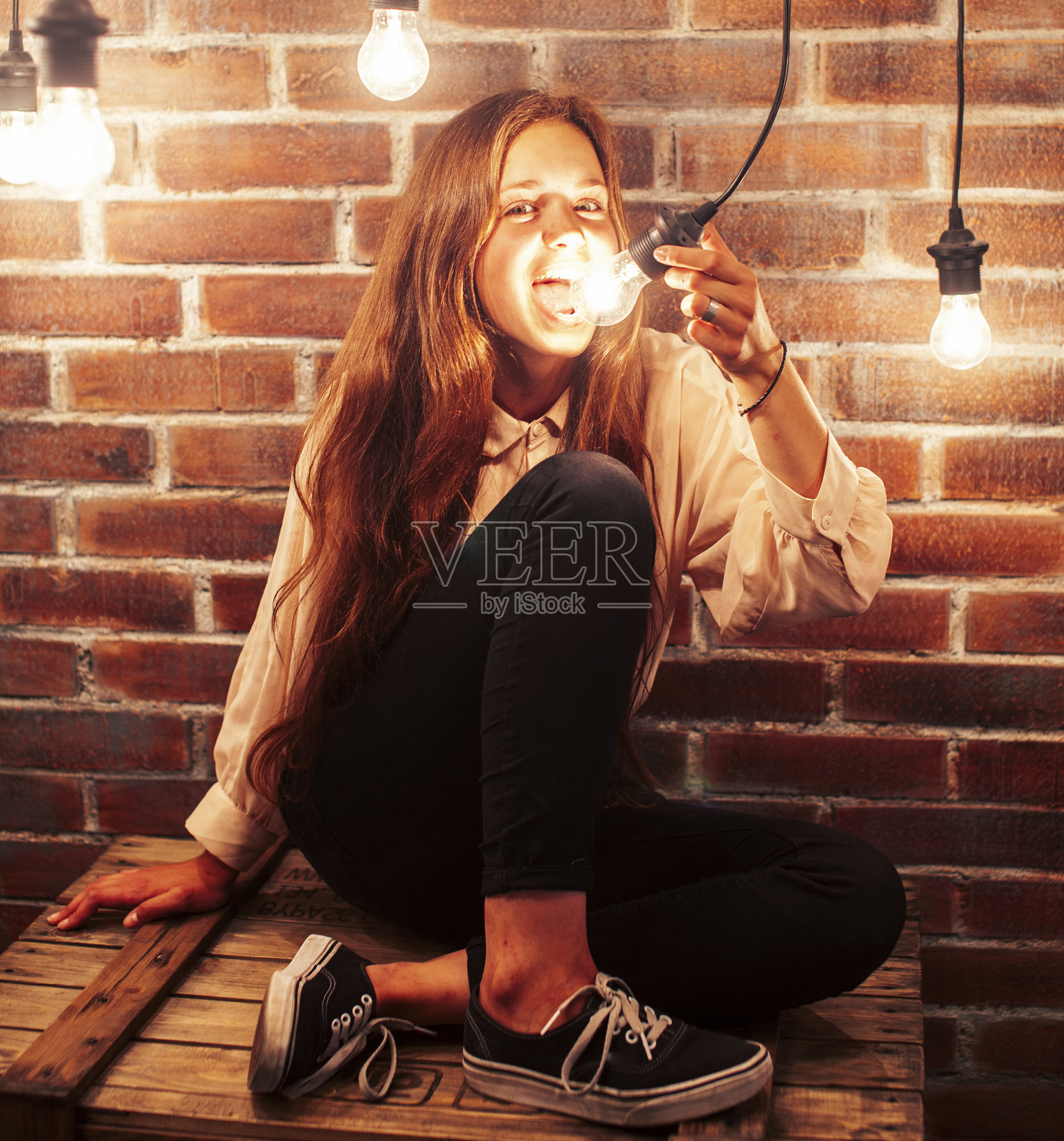 年轻的十几岁的女孩摆出欢快的姿势在现代阁楼工作室室内与许多灯，生活方式度假的人的概念照片摄影图片