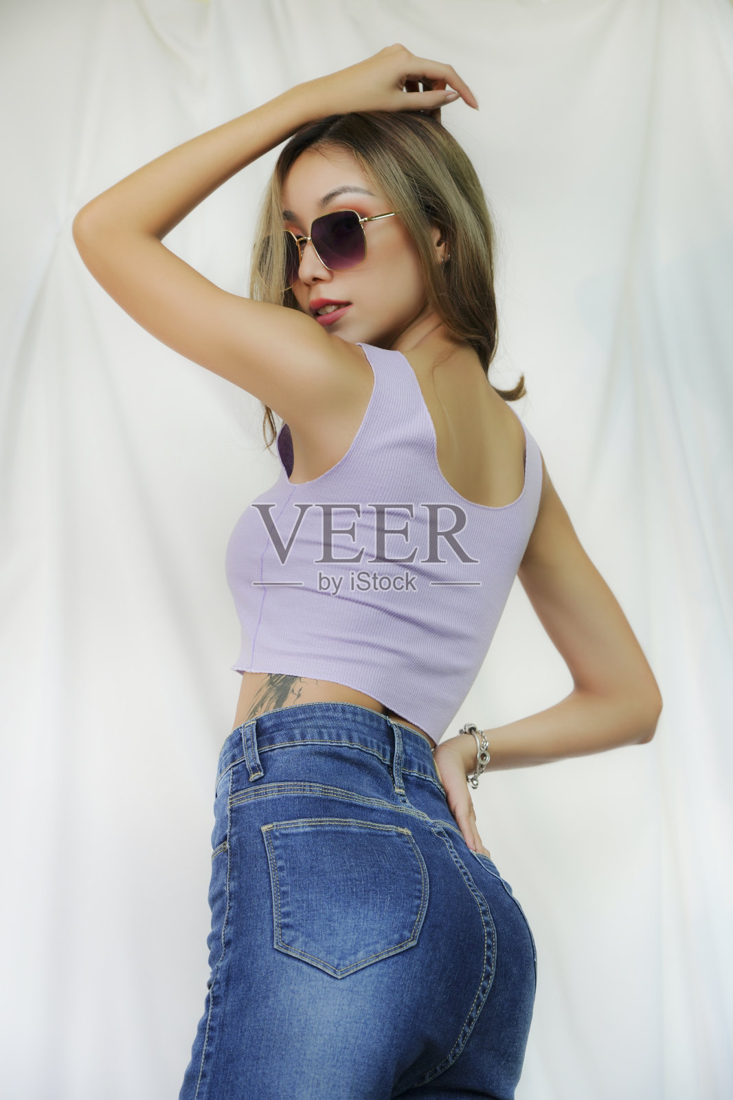 美容时尚女孩与纹身。身材苗条的女人穿着露脐上衣的肖像。照片摄影图片