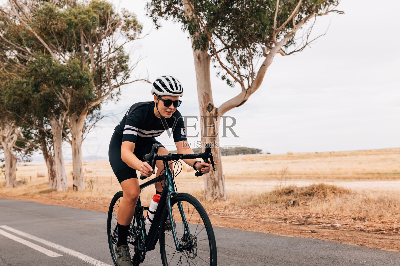 女自行车手骑着她的职业自行车在乡村道路上快速照片摄影图片