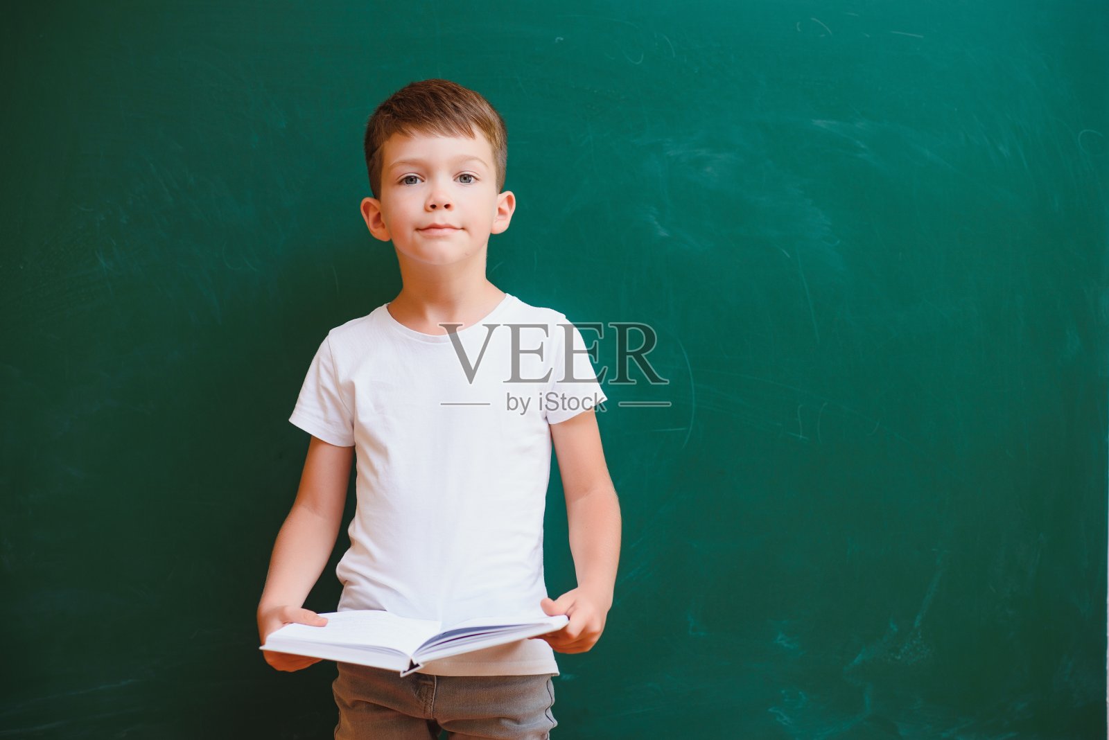 有趣的男孩在教室里的绿色学校董事会附近。小学。回到学校。照片摄影图片