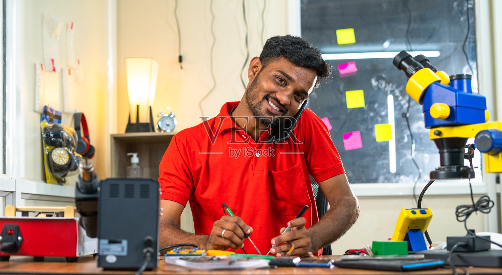 移动技术人员在车间用手机与客户交谈-放松、客户服务和沟通的概念。照片摄影图片