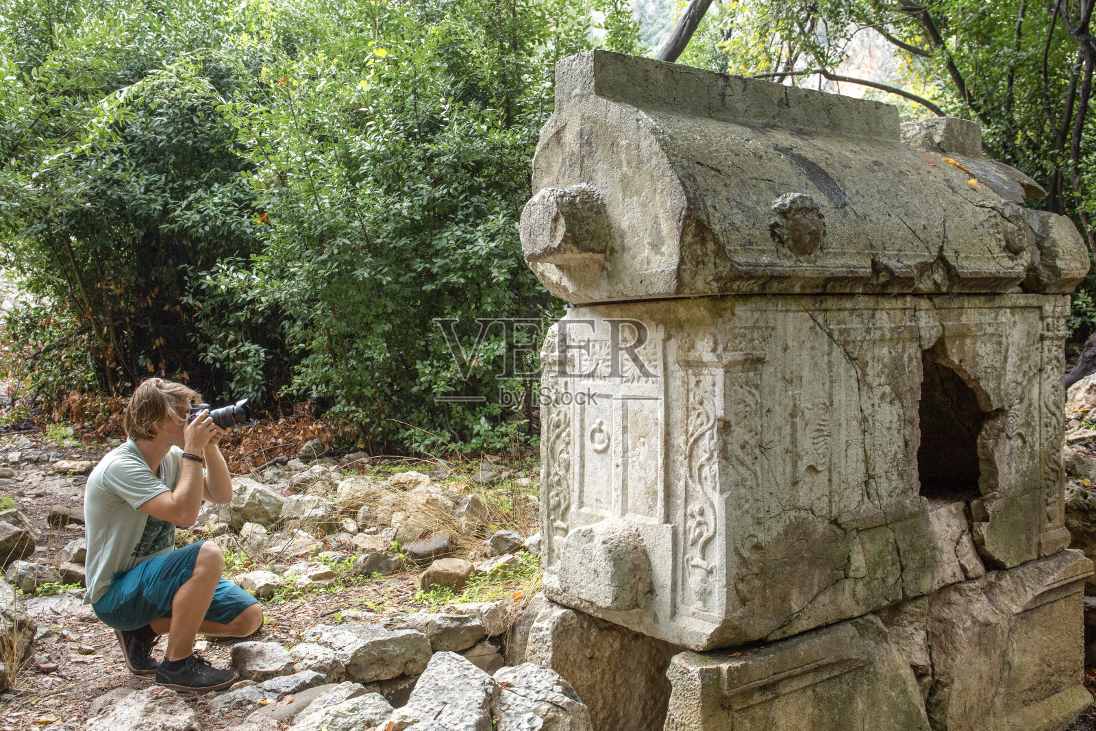 年轻人在森林里拍摄石棺照片摄影图片