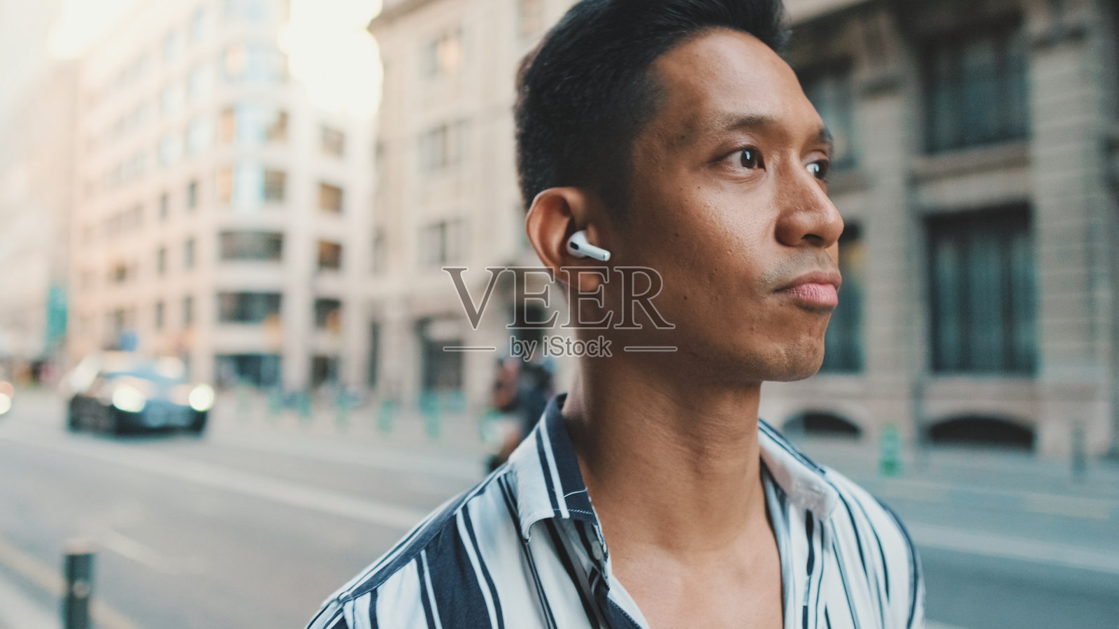 年轻人走在路边，戴着耳机听音乐照片摄影图片