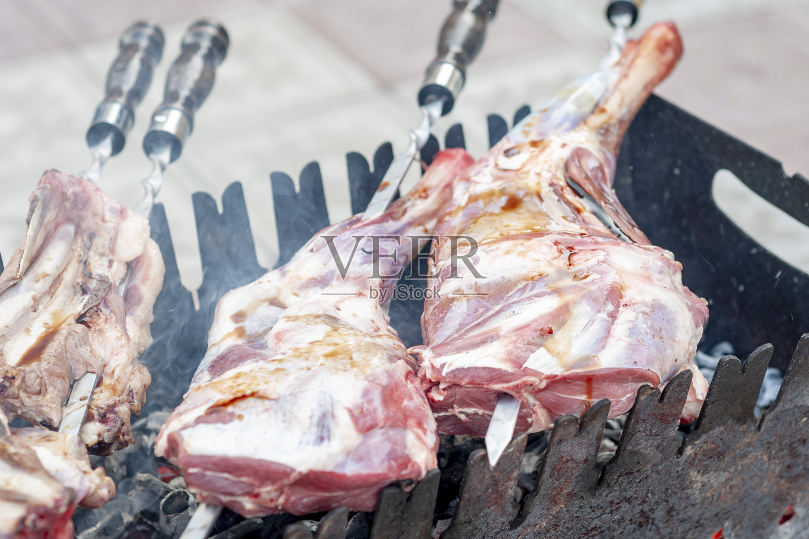 生的羊腿和排骨，浇上酱油，串在串上，放在烤架上。照片摄影图片