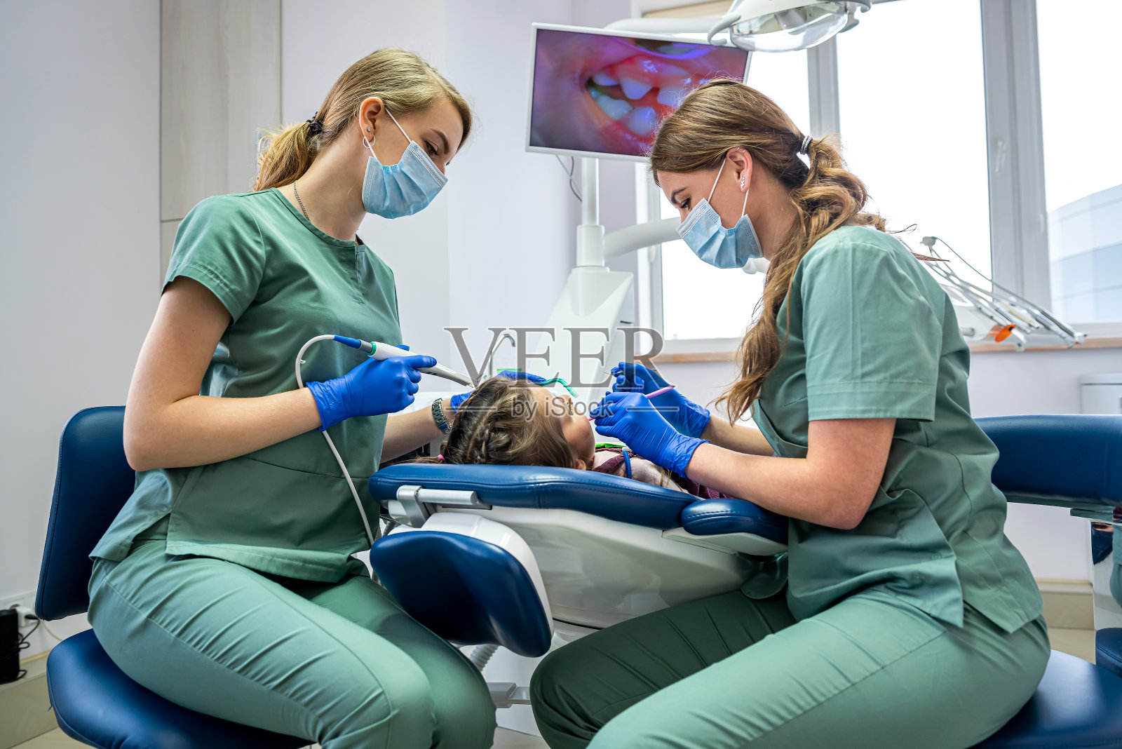 牙医通过屏幕上显示的摄像头对小病人进行检查。照片摄影图片