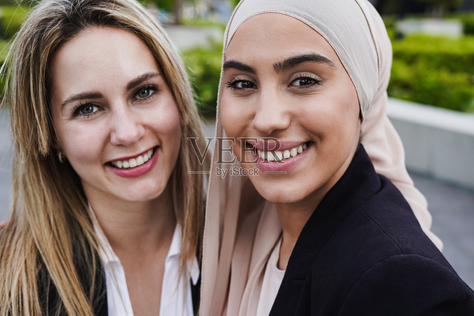 年轻的多元种族商业女性在办公楼外的午休时间对着镜头微笑照片摄影图片