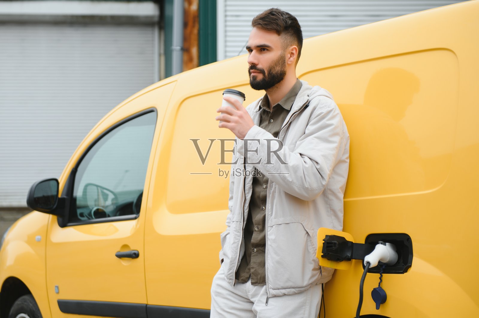 男子在工作时给电动汽车充电照片摄影图片