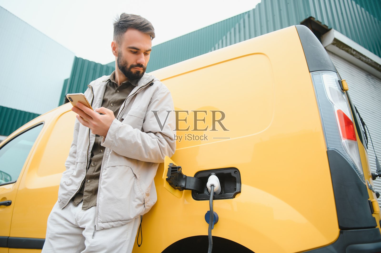 男子正在给他的电动汽车充电。照片摄影图片