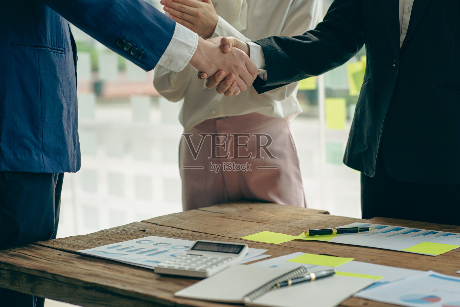 两个商务人士在会议中握手，接触，问候商业伙伴。在设定目标和计划成功的方法后，用图表纸和笔记，伙伴关系的想法和团队合作。照片摄影图片