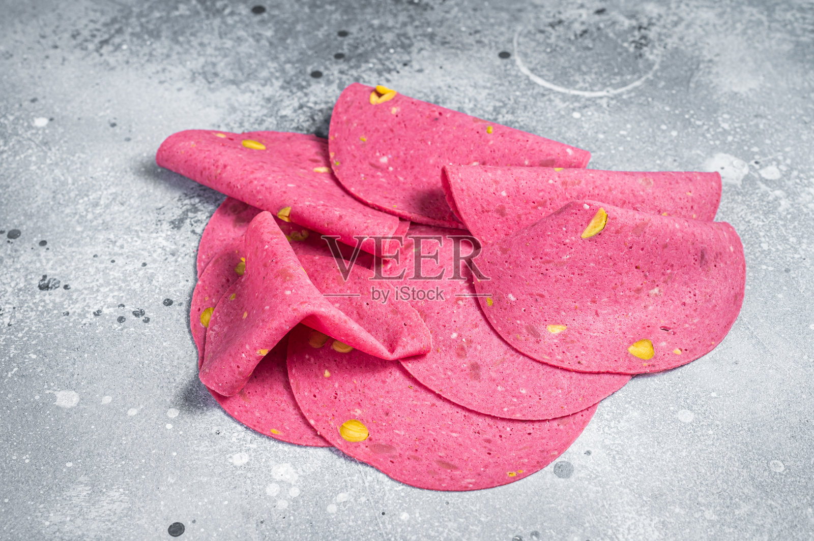 厨房桌上放着摩泰台拉腊肠，开心果和黑胡椒。灰色的背景。俯视图照片摄影图片