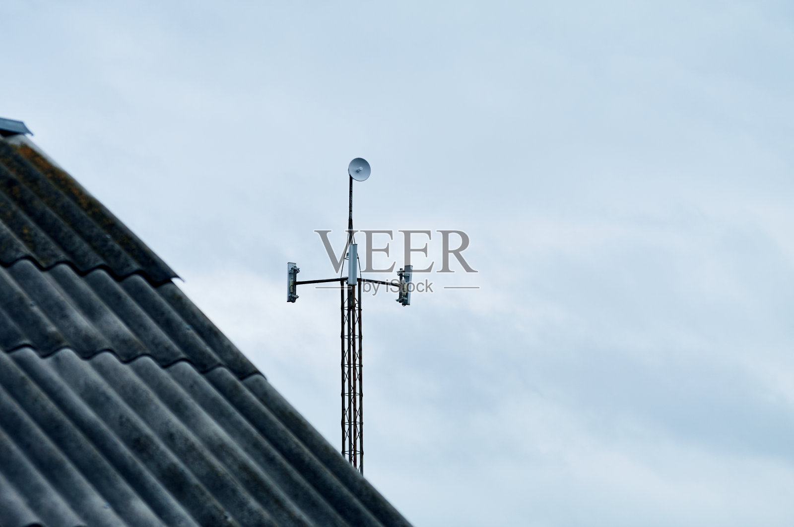 因为旧的石板屋顶，你可以看到一个带有天线的现代塔，天线播放Wi-Fi互联网信号照片摄影图片