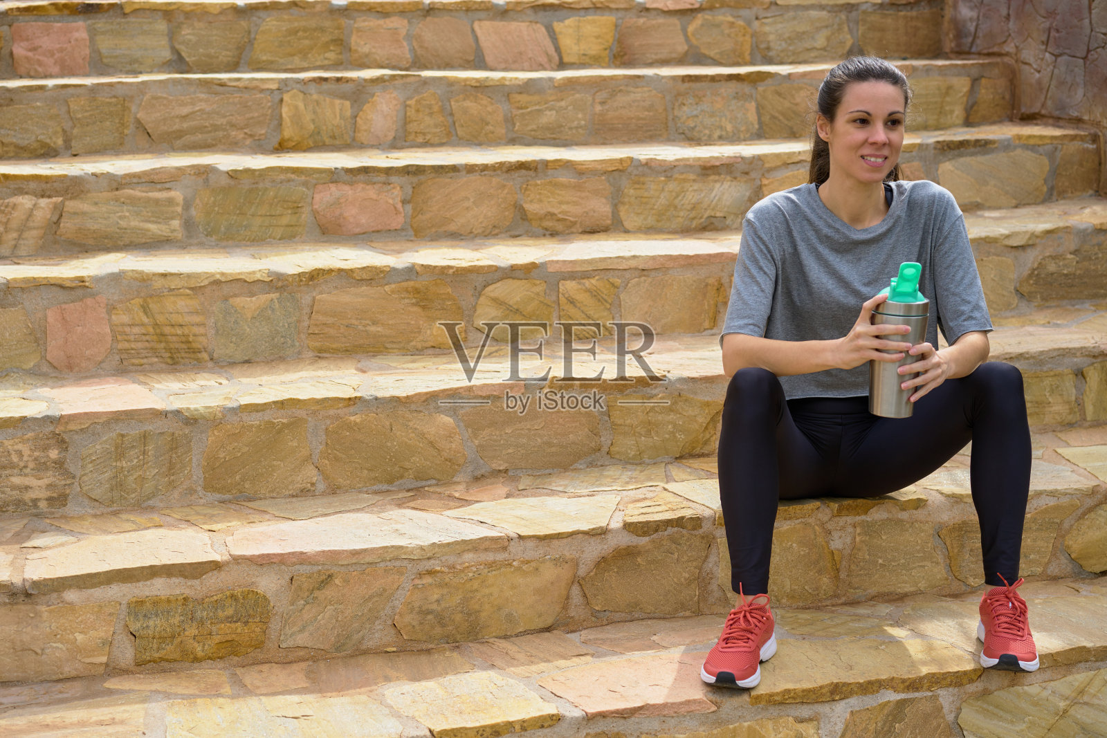 坐在楼梯上拿着环保铝瓶的女运动员照片摄影图片