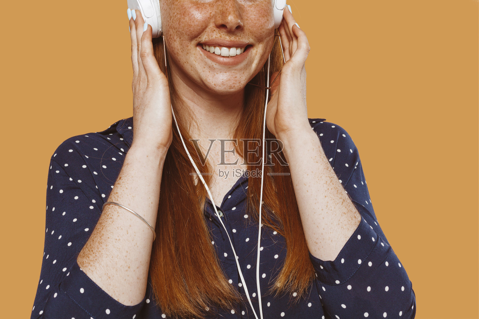 开朗的红发女孩用手戴着耳机听音乐照片摄影图片