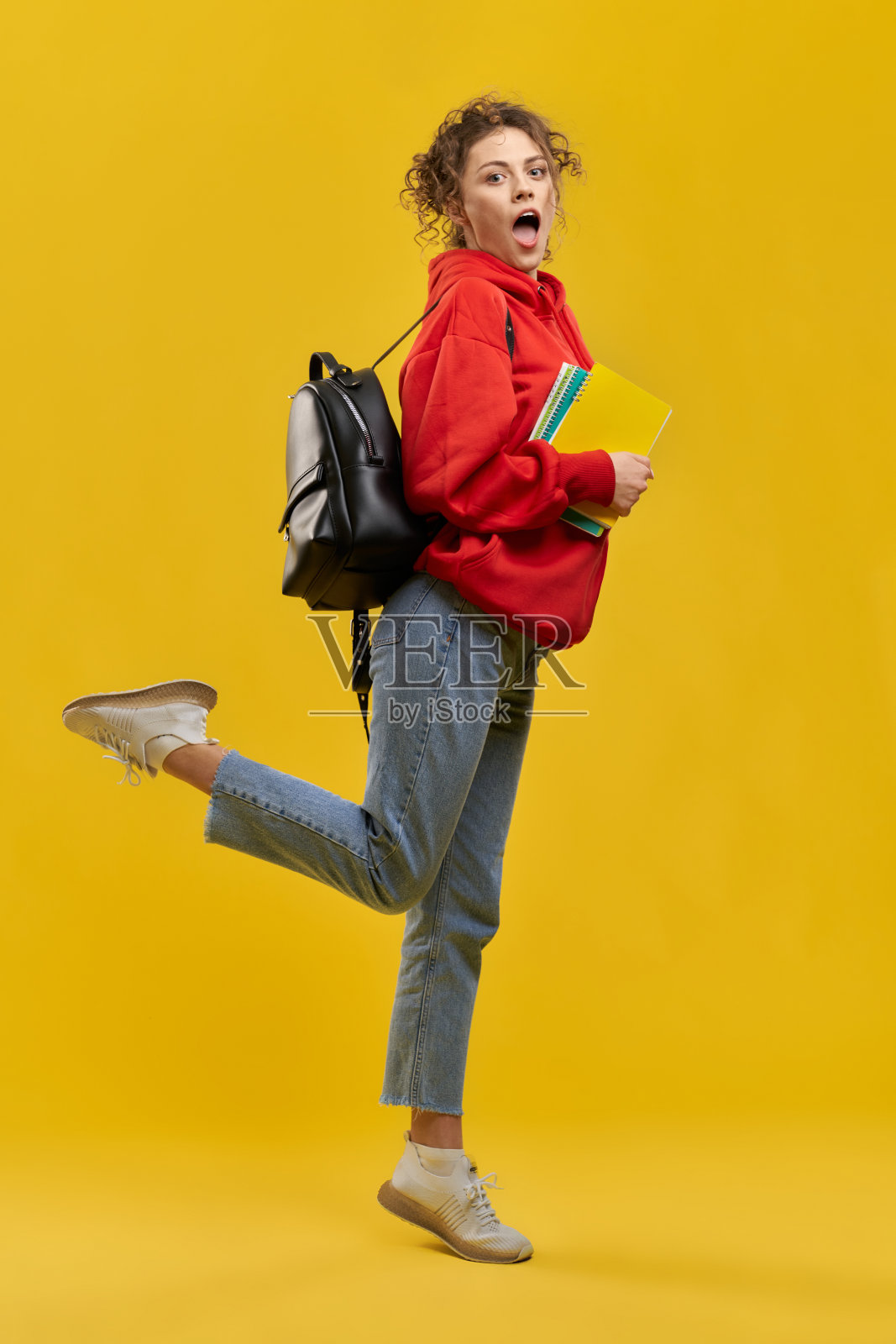 学生拿着书站着，抬腿。照片摄影图片