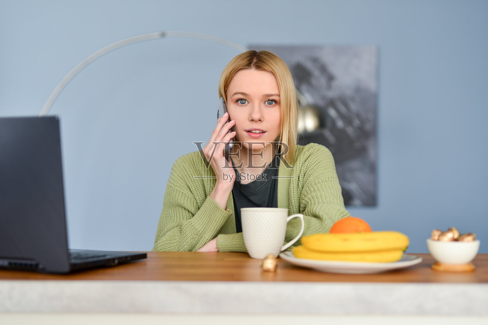 年轻女性在家里的厨房里用智能手机照片摄影图片